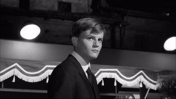 Movie still from “Girl with a Suitcase” (1961), directed by Valerio Zurlini – A man in a suit and tie standing in front of a building; Close Up shot, Low angle
