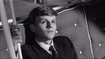 Movie still from “Girl with a Suitcase” (1961), directed by Valerio Zurlini – A man in a suit and tie sitting in front of a chair; Close Up shot, High angle
