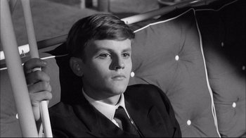 Movie still from “Girl with a Suitcase” (1961), directed by Valerio Zurlini – A young man wearing a suit and tie sitting down; Close Up shot, High angle
