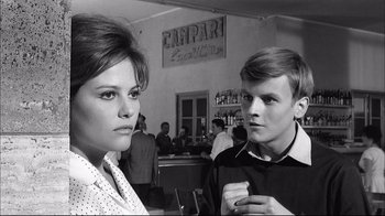 Movie still from “Girl with a Suitcase” (1961), directed by Valerio Zurlini – A man and a woman standing next to each other in a restaurant; Medium shot, Over the shoulder angle