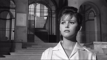 Movie still from “Girl with a Suitcase” (1961), directed by Valerio Zurlini – A young woman standing in front of an iron gate; Close Up shot, Low angle