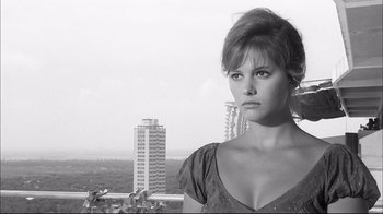Movie still from “Girl with a Suitcase” (1961), directed by Valerio Zurlini – A black - and - white photo of a woman in front of a city skyline; Close Up shot, Low angle