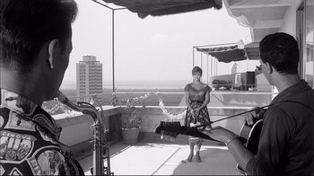 Movie still from “Girl with a Suitcase” (1961), directed by Valerio Zurlini – A black and white photo of a woman and a cat on a balcony; Wide shot, Low angle