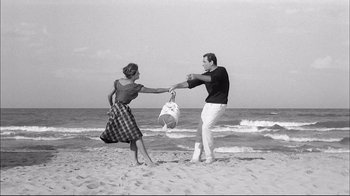 Movie still from “Girl with a Suitcase” (1961), directed by Valerio Zurlini – A man and a woman on the beach holding hands; Wide shot, Low angle
