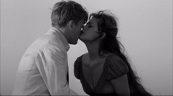 Movie still from “Girl with a Suitcase” (1961), directed by Valerio Zurlini – A man and a woman kissing each other in front of a white wall; Medium shot, Over the shoulder angle