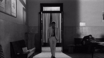 Movie still from “Girl with a Suitcase” (1961), directed by Valerio Zurlini – A black and white photo of a man standing in front of a door; Wide shot, Low angle