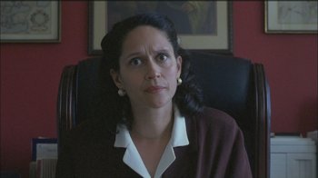 Movie still from “Girlfight” (2000), directed by Karyn Kusama – A woman sitting in a chair in front of a painting; Close Up shot, Low angle