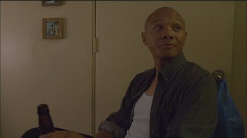 Movie still from “Girlfight” (2000), directed by Karyn Kusama – A man sitting in front of a wall looking into the distance; Medium shot, Low angle