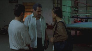 Movie still from “Girlfight” (2000), directed by Karyn Kusama – A man talking to two young people in a room; Medium shot, Over the shoulder angle