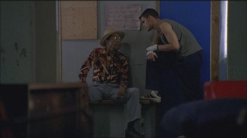 Movie still from “Girlfight” (2000), directed by Karyn Kusama – A man talking to an older man sitting on a chair; Wide shot, Over the shoulder angle