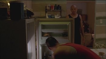 Movie still from “Girlfight” (2000), directed by Karyn Kusama – A man looking into a refrigerator while another man stands in the background; Medium shot, Low angle