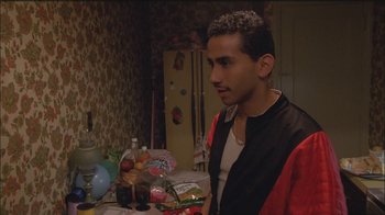 Movie still from “Girlfight” (2000), directed by Karyn Kusama – A man standing in front of a table filled with food; Medium shot, Over the shoulder angle