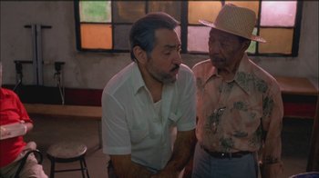Movie still from “Girlfight” (2000), directed by Karyn Kusama – A man in a hat and a man in a white shirt talking to each other; Medium shot, High angle