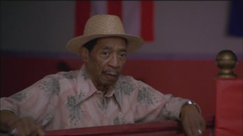 Movie still from “Girlfight” (2000), directed by Karyn Kusama – An older man wearing a straw hat sitting in a booth; Close Up shot, Low angle