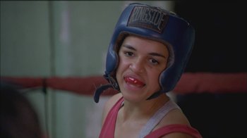 Movie still from “Girlfight” (2000), directed by Karyn Kusama – A young woman wearing a boxing helmet in a boxing ring; Close Up shot, High angle