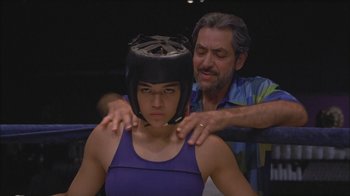 Movie still from “Girlfight” (2000), directed by Karyn Kusama – A man putting a helmet on a woman's head; Close Up shot, Over the shoulder angle