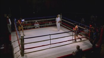 Movie still from “Girlfight” (2000), directed by Karyn Kusama – Two men in a boxing ring in front of a crowd of people; Wide shot, High angle