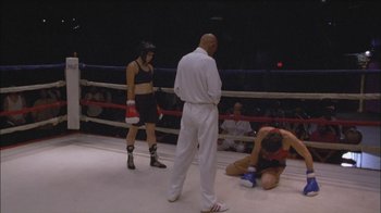 Movie still from “Girlfight” (2000), directed by Karyn Kusama – A woman in a boxing ring with a referee and a man; Wide shot, Over the shoulder angle