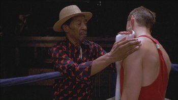 Movie still from “Girlfight” (2000), directed by Karyn Kusama – An older man wearing a straw hat is shaving his face; Medium shot, Over the shoulder angle