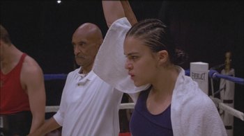 Movie still from “Girlfight” (2000), directed by Karyn Kusama – A young woman raises her hand in a boxing ring; Medium shot, Low angle