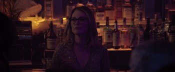 Movie still from “Gloria Bell” (2018), directed by Sebastián Lelio – A woman with glasses is standing in front of a bar; Close Up shot, Over the shoulder angle