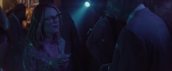 Movie still from “Gloria Bell” (2018), directed by Sebastián Lelio – A group of people standing in a dark room talking; Medium shot, Over the shoulder angle