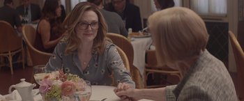 Movie still from “Gloria Bell” (2018), directed by Sebastián Lelio – A woman sitting at a table with a woman holding her hand; Medium shot, Over the shoulder angle