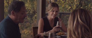 Movie still from “Gloria Bell” (2018), directed by Sebastián Lelio – A woman sitting at a dinner table holding a glass of wine; Medium shot, Over the shoulder angle