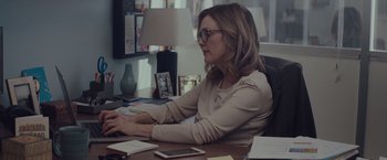 Movie still from “Gloria Bell” (2018), directed by Sebastián Lelio – A woman sitting at a desk working on a computer; Medium shot, Over the shoulder angle