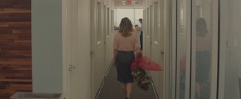 Movie still from “Gloria Bell” (2018), directed by Sebastián Lelio – A woman walking down a hallway holding flowers; Wide shot, High angle