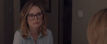 Movie still from “Gloria Bell” (2018), directed by Sebastián Lelio – A woman wearing glasses sitting in front of a wall; Close Up shot, Over the shoulder angle