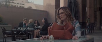 Movie still from “Gloria Bell” (2018), directed by Sebastián Lelio – A woman sitting at a table with a purse; Medium shot, Over the shoulder angle