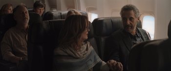 Movie still from “Gloria Bell” (2018), directed by Sebastián Lelio – A woman sitting on an airplane with her hand on her chin; Medium shot, Over the shoulder angle