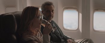 Movie still from “Gloria Bell” (2018), directed by Sebastián Lelio – A man and a woman sitting on an airplane drinking wine; Medium shot, Over the shoulder angle