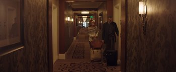 Movie still from “Gloria Bell” (2018), directed by Sebastián Lelio – A man and a woman pulling suitcases in a hotel hallway; Wide shot, High angle