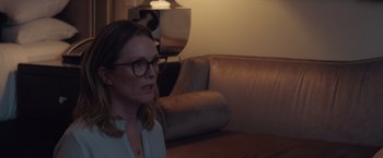 Movie still from “Gloria Bell” (2018), directed by Sebastián Lelio – A woman wearing glasses is sitting on a couch; Medium shot, Over the shoulder angle