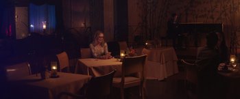 Movie still from “Gloria Bell” (2018), directed by Sebastián Lelio – A woman sitting at a table in front of candles; Wide shot, High angle