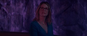 Movie still from “Gloria Bell” (2018), directed by Sebastián Lelio – A woman wearing glasses sitting in front of a purple background; Medium shot, Low angle
