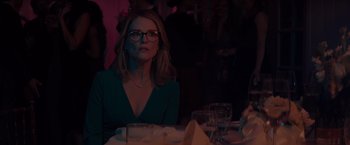 Movie still from “Gloria Bell” (2018), directed by Sebastián Lelio – A woman sitting at a dinner table looking at the camera; Medium shot, Over the shoulder angle
