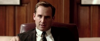 Movie still from “Glory Road” (2006), directed by James Gartner – A man in a suit and tie sitting in a chair; Close Up shot, Over the shoulder angle