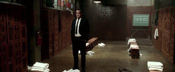 Movie still from “Glory Road” (2006), directed by James Gartner – A man in a suit and tie standing in a room; Medium shot, Low angle