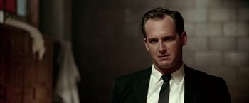 Movie still from “Glory Road” (2006), directed by James Gartner – A man wearing a suit and tie in front of a wall; Close Up shot, Low angle