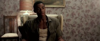 Movie still from “Glory Road” (2006), directed by James Gartner – A man sitting in a chair in front of a painting; Close Up shot, High angle