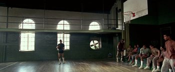 Movie still from “Glory Road” (2006), directed by James Gartner – Two men are standing in a room with a large window; Wide shot, Low angle