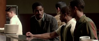 Movie still from “Glory Road” (2006), directed by James Gartner – A group of young men standing around a table; Medium shot, Over the shoulder angle