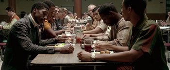 Movie still from “Glory Road” (2006), directed by James Gartner – A group of people sitting at a long table eating food; Medium shot, High angle
