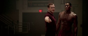 Movie still from “Glory Road” (2006), directed by James Gartner – A man standing in front of another man in a gym; Medium shot, Over the shoulder angle