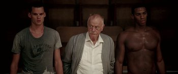 Movie still from “Glory Road” (2006), directed by James Gartner – An old man wearing a white shirt and a gray jacket; Medium shot, Low angle