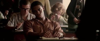 Movie still from “Glory Road” (2006), directed by James Gartner – A man sitting at a table writing on a piece of paper; Close Up shot, Over the shoulder angle
