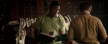 Movie still from “Glory Road” (2006), directed by James Gartner – A man in a green shirt is holding a notebook; Medium shot, Over the shoulder angle